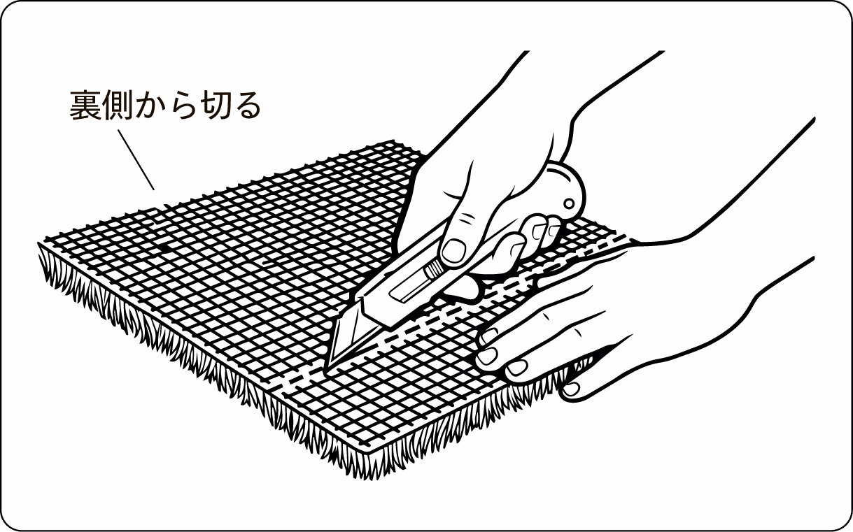 人工芝を裏返し、裏側からカッターの刃を入れて切っている図