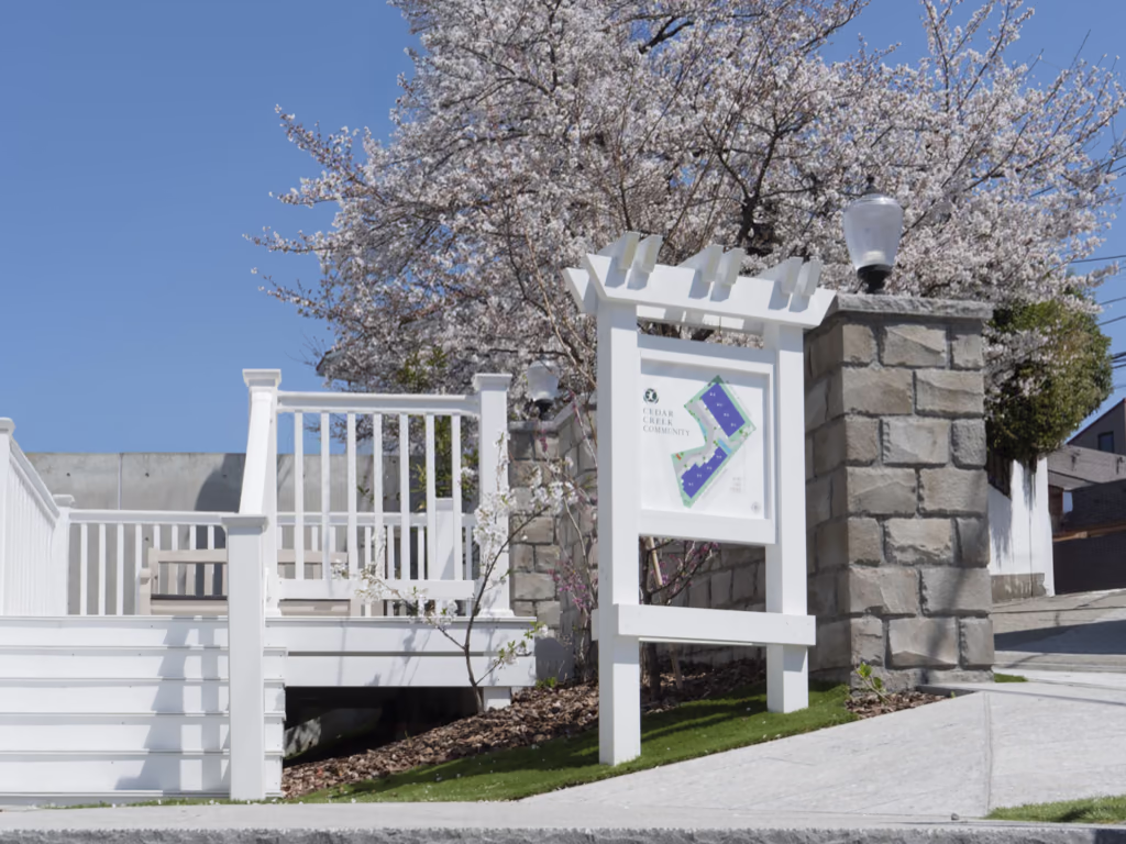 桜の咲く集合住宅の入口。ホワイトのバイナルフェンスで手すりを揃えたコモンスペース