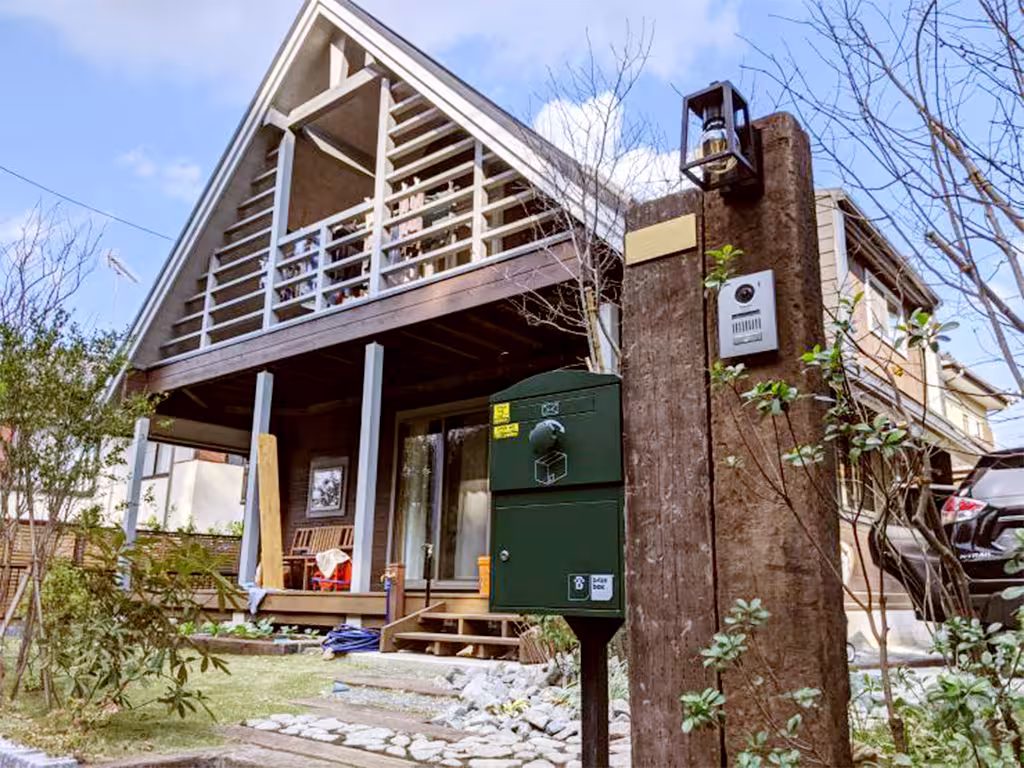 戸建て住宅の玄関に置かれたグリーンの宅配ボックス。おしゃれな門柱と調和し、不在時も荷物を受け取れる便利な宅配ボックスです。