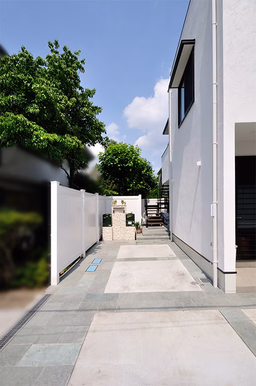 白い目隠しフェンスと門柱が続く、新築住宅のアプローチ