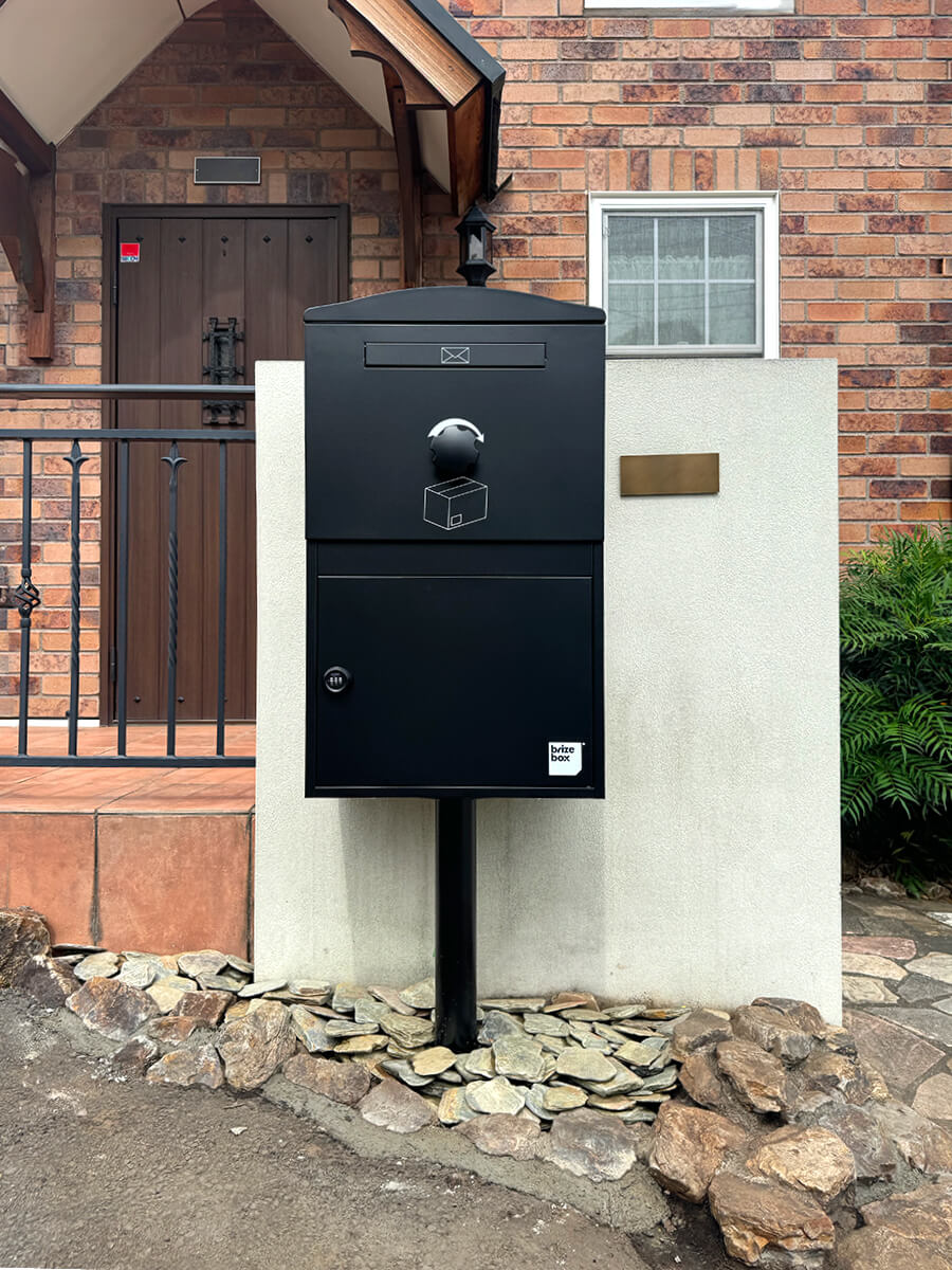 ブラックのBrizebox（Largeサイズ）を塗り壁の門柱にポール施工した戸建ての宅配ボックス施工例